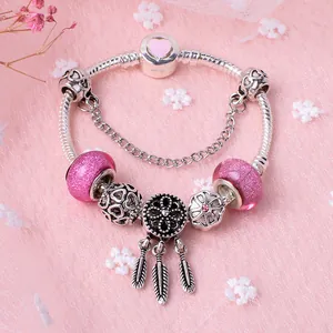 Pink heart charm bracelet with glass beads and dreamcatcher pendant on pink fabric