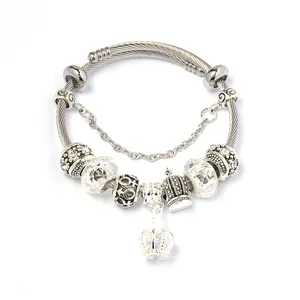 Detail van een zilveren kralenarmband met kristallen kralen en een kroonhanger