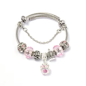 Detail van zilveren gedraaide armband met roze kristallen kralen en kroonbedeltje