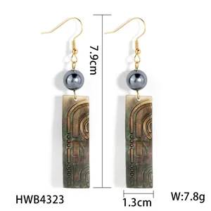 Boucles d'oreilles pendantes dorées avec perle grise et pendentifs en nacre noire sculptée