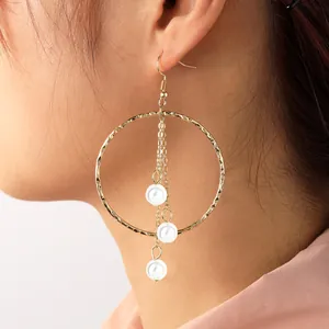 Detail of long drop earrings with gold textured hoop and cascading green pearls