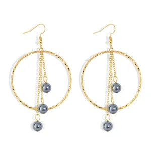Detail of gold hammered hoop earrings with triple hanging chains and grey pearl accents