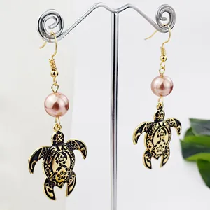 Detailansicht der Schildkröten-Ohrringe mit rosa Perle und schwarzem Tropföl-Muster