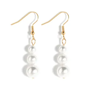 Detail van elegante gouden oorbellen met drie gegradueerde witte parels op witte basis