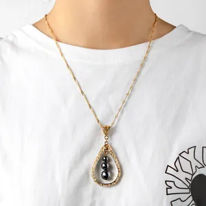 Detail van vintage druppelketting met goudkleurige filigraan en zwarte parels op model