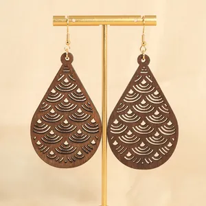 Elegante Wassertropfen-Holzohrringe mit goldenen Haken auf einem minimalistischen Schmuckständer