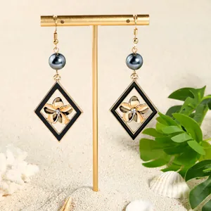 Gros plan de boucles d'oreilles fleur dorée avec perles et diamants sur sable