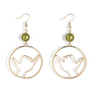 Detail of Shaka gesture earrings featuring golden frames and olive green pearls