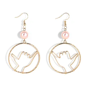 Detail of Shaka hand gesture earrings with pink pearls and golden wire hook