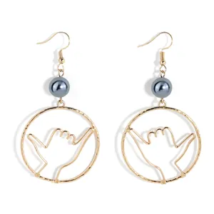 Detail view of gold Hawaii Shaka hand gesture earrings with grey pearl accents