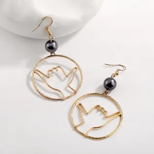 Detail of gold shaka sign hoop earrings with grey pearls on minimalist white background