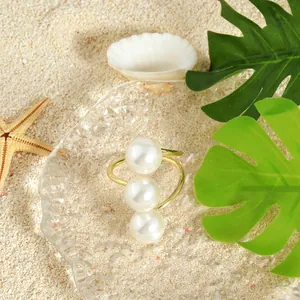Anello aperto con tre perle finitura oro 14k su vassoio decorativo da spiaggia