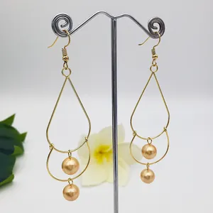 Detail of gold double-layered teardrop earrings with dangling metallic pearls