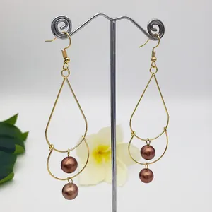 Detail of vintage gold drop earrings with brown pearls hanging on a display stand