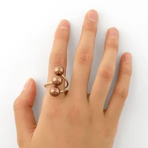 Dettaglio di tre perle di conchiglia marroni su un anello aperto placcato in oro 14k
