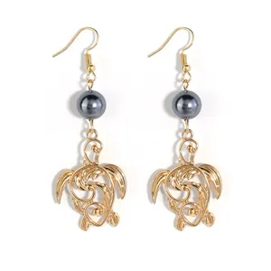 Boucles d'oreilles tortue dorée avec perles gris foncé et motifs complexes de l'océan