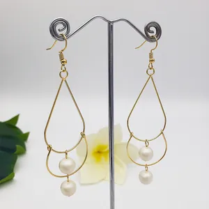 Detail of elegant gold-tone layered frame earrings with two white pearl accents