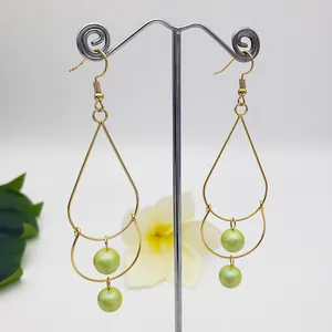 Detail of gold teardrop earrings with double metal hoops and light green pearls