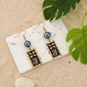 Gros plan de boucles d'oreilles pendantes carrées vintage avec perles sur fond tropical