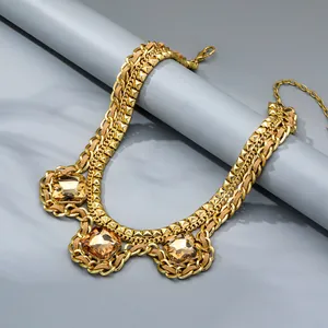 Detail of chunky gold chain necklace with woven brown cord and amber crystal pendants