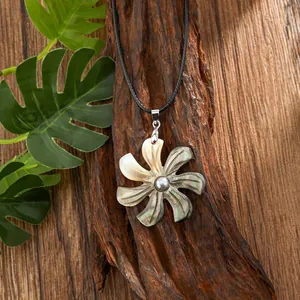 Detail of hand-carved shell flower pendant with grey pearl on black cord necklace