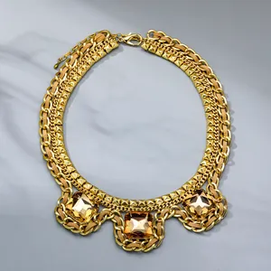 Detailed view of layered gold cuban chain necklace with amber zircon stone pendant