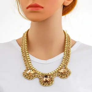 Detail of layered gold-plated chain necklace featuring three square brown gemstones