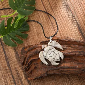 Macro shot of carved natural shell turtle pendant with iridescent luster on black cord