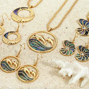 Detail of nautical jewelry set with natural abalone shell in gold dolphin shell design