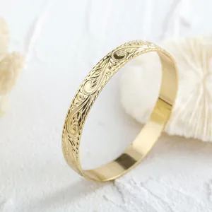Detail eines 14k vergoldeten Hawaii-Armreifs mit feiner Ranken- und Frangipani-Gravur