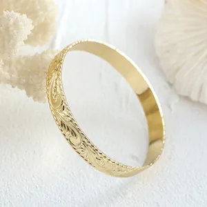 Detail eines 14k vergoldeten Armreifs mit Hawaii-Gravur und gewelltem Rand Design