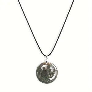 Detail of a turtle pendant crafted from iridescent black mother of pearl shell