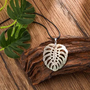 Macro detail of leaf-shaped seashell pendant on rustic wood background with natural luster