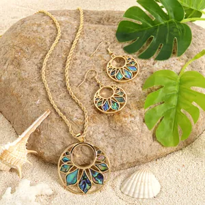 Golden sunflower jewelry set with natural abalone shell on beach stones and leaves