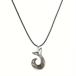 Detailed macro of a carved natural shell fish hook pendant on a black cord necklace
