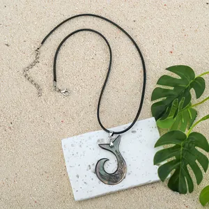 Macro view of shell fish hook pendant with ethnic motifs and black velvet cord