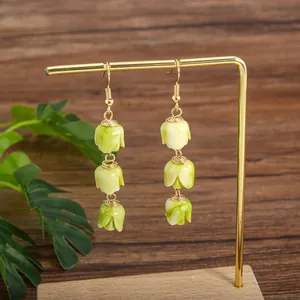 Macro detail of handmade gold-wired tulip bud drop earrings with green marble texture