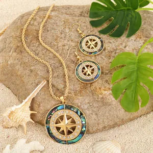 Detail of sunflower compass jewelry set with abalone shell inlays on sandy beach