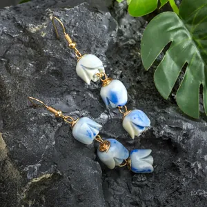 Handmade wire-wrapped tulip drop earrings with blue gradient beads on stone background