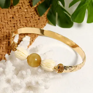 Detail of gold-plated bohemian bangle with tiger eye stone and ivory flower accents