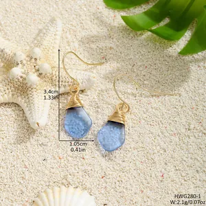Handgefertigte Meerglas-Ohrringe mit Golddrahtwicklung und Maßangaben am Strand