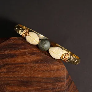 Close-up of gold beaded bracelet with green tiger eye and resin jasmine flower detail