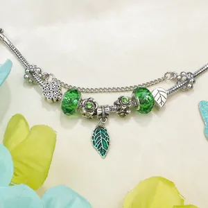 Detailed shot of clover leaf charm bracelet with green crystals on textured beige fabric