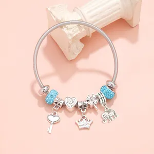 Pink charm bracelet with silver crown, heart, and blue crystal beads on pink background