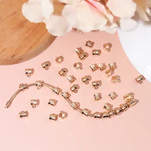 Golden cylinder spacer beads with ring and snake chain on decorative background