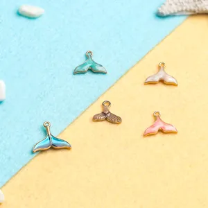 Five colorful enamel mermaid tail charms for DIY jewelry on an ocean themed background