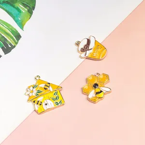 Detail of bee and honey jar charms in yellow enamel with gold metal trim for jewelry making