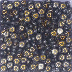 Detailed macro of 7mm black round acrylic beads with golden hearts for DIY bracelets