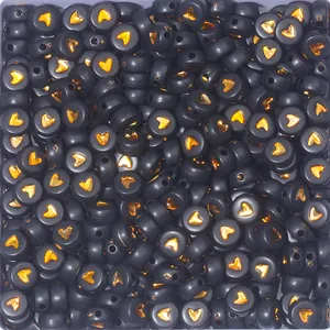 Macro view of matte black flat round beads with gold heart patterns for DIY jewelry