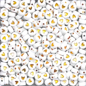 Flat lay detail of round white beads with golden heart designs for DIY bracelets